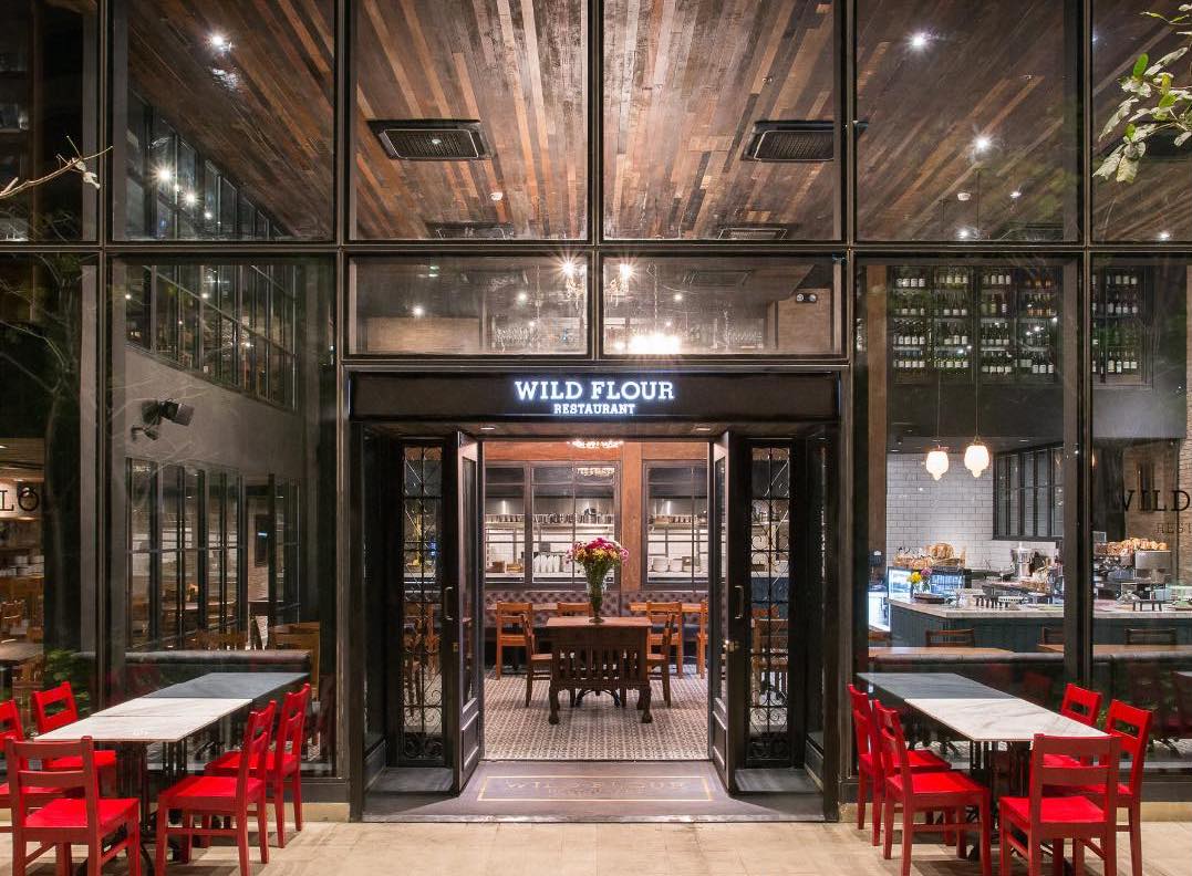 Wildflour Rockwell exterior with red chairs and wooden ceiling